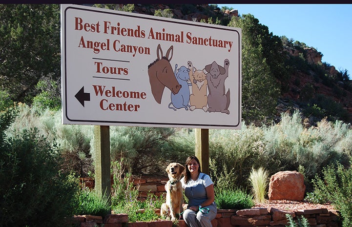 Ava the dog and a woman sitting under the Best Friends Animal Sanctuary sign