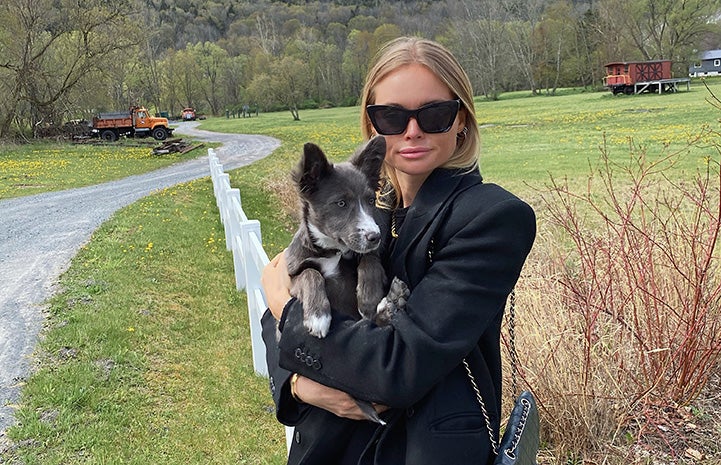 Claire Rose holding Billie, the puppy she adopted, in a grassy field