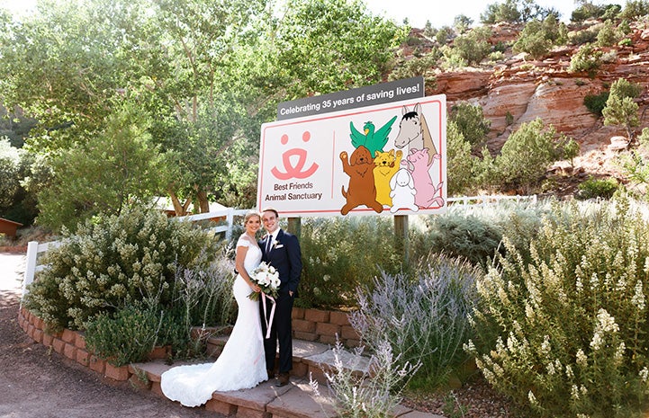 Haley and Kevin in their wedding clothes in front of the Best Friends Animal Sanctuary sign