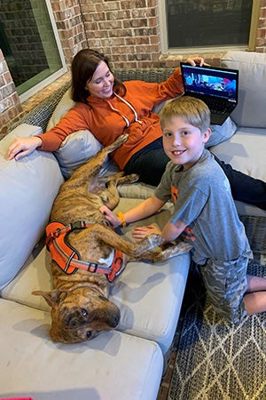 Woman and young boy next to Pancho the dog who is lying on a couch