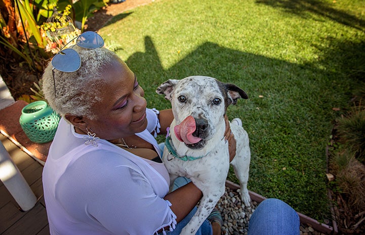 Woman hugging Seven the dog, who is licking her lips