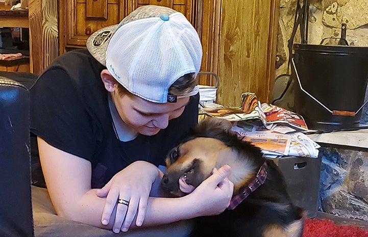 Max the dog giving a kiss to a person wearing a backwards baseball hat