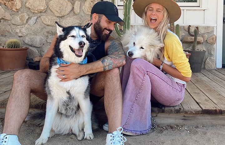 Tyler Rich and his wife smiling and posting with two dogs