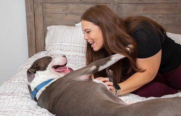 Jacqui Campos lying on a bed with Neville the dog looking lovingly at him