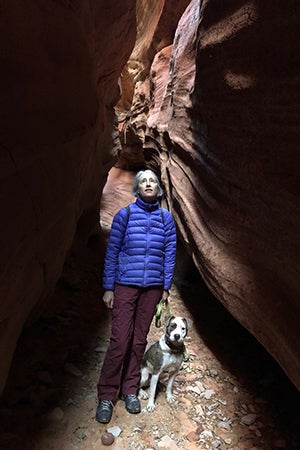Volunteer Heather Harding hiking with Pilsner the dog in a slot canyon