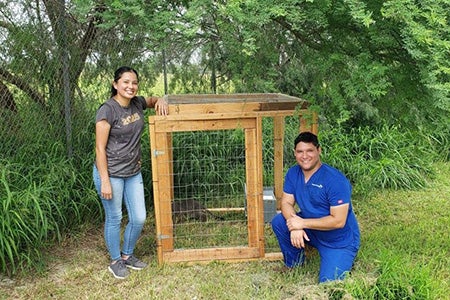 Terri and Jason standing next to a wooden structure designed to acclimate community cats to a new location