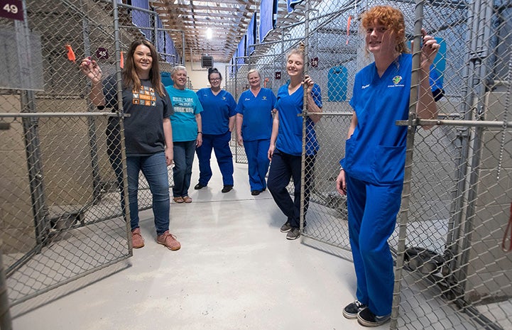 SRCAS staff smiling in front of empty kennels