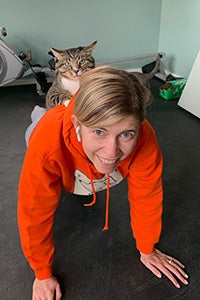 Woman doing a plank exercise with a cat on her back