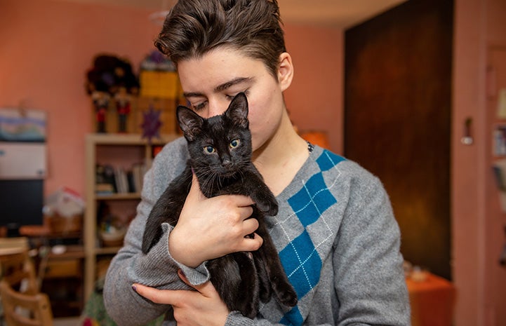 Jelly the black cat being held by a woman