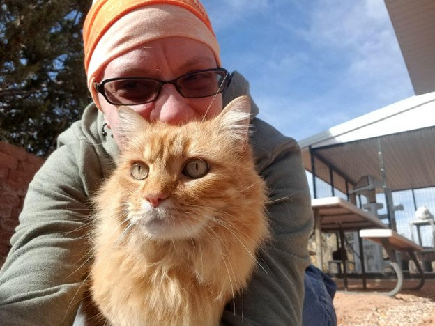 Caregiver Jessica with Hermes the orange longhair tabby cat outside