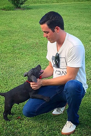 Alex Bowman kneeling in the grass with his dog when a puppy