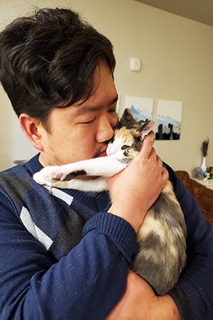 Person holding and kissing a calico kitten