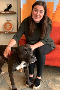 Woman sitting down next to foster dog Morgan Freeman