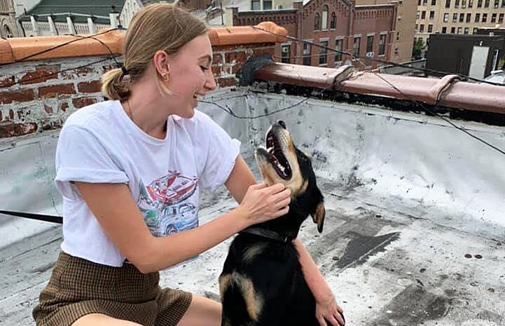 Woman squatting down during a walk to pet Wentworth the dog