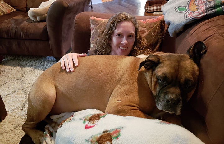 Woman lying on the couch with Beau the foster dog lying on her lap