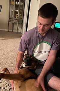 Man cuddling with Almond the dog while on the floor