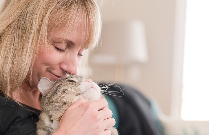 A smiling Jennifer Bigler snuggling with Mr. Cheeks the cat