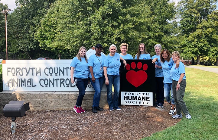 Group of people posing in front of the Forsyth Humane Society sign