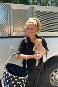 Smiling woman holding Pennywise the orange tabby kitten