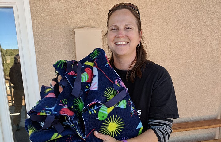 Woman holding a pile of blankets being donated to Dogtown
