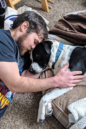 Mulligan, a black and white pit-bull-terrier-type dog, sleeping head-to-head with his adopter Matt