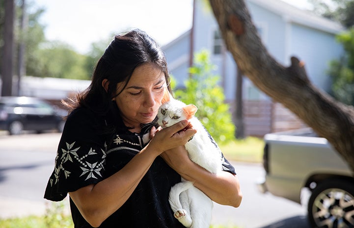 Woman from Palm Valley Animal Society walking outside and holding a white, ear-tipped cat