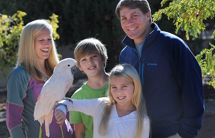The Scharf family smiling and Berkeley holding a parrot