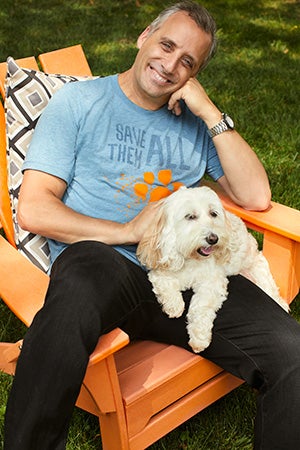 Joe Gatto wearing a Best Friends Save Them All T-shirt and holding a white dog