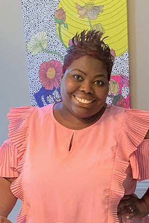 Head shot of Shafonda Davis wearing a ruffled top with a colorful floral picture in the background