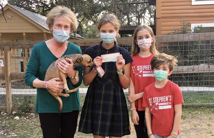 Lucy, Claire and Emmelia presenting a check to a woman from WAGS holding a puppy