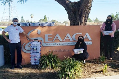 People standing in by the SEAACA sign with stacks of kitten kits