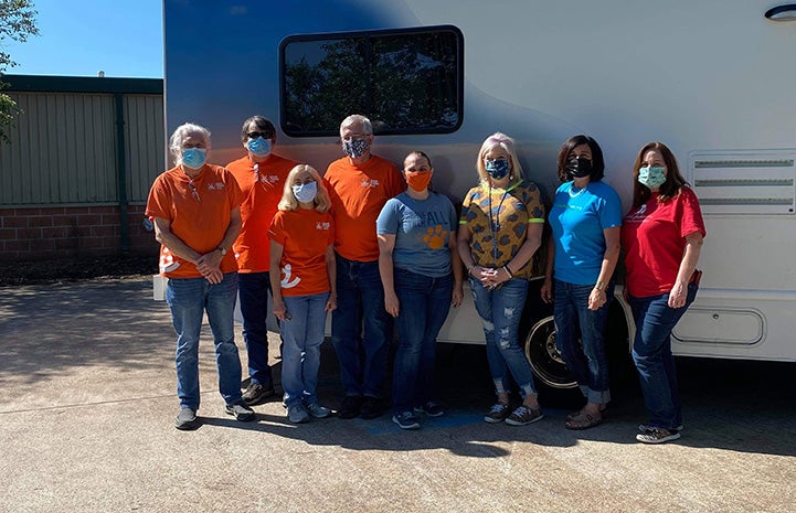 Masked group of people, many wearing Best Friends shirts, posing in front of the transport RV