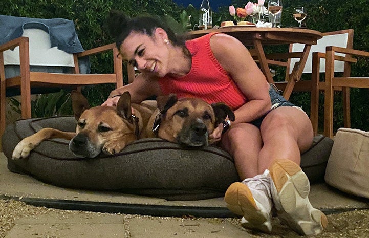 Woman lying on a cushion with Bear and Austin the dogs