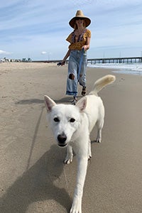 Woman walking Luna the dog on a leash on a beach