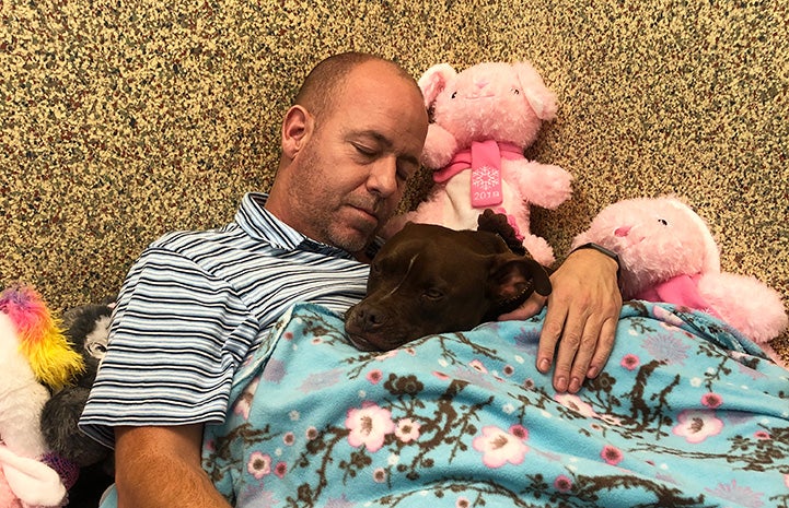 Scott Poore sleeping next to Queen the dog at the shelter