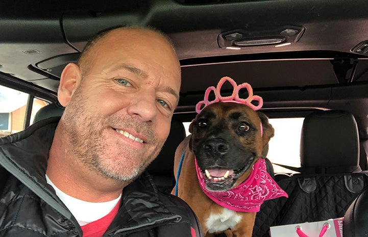 Scott Poore in a car next to a pit bull type dog wearing a tiara