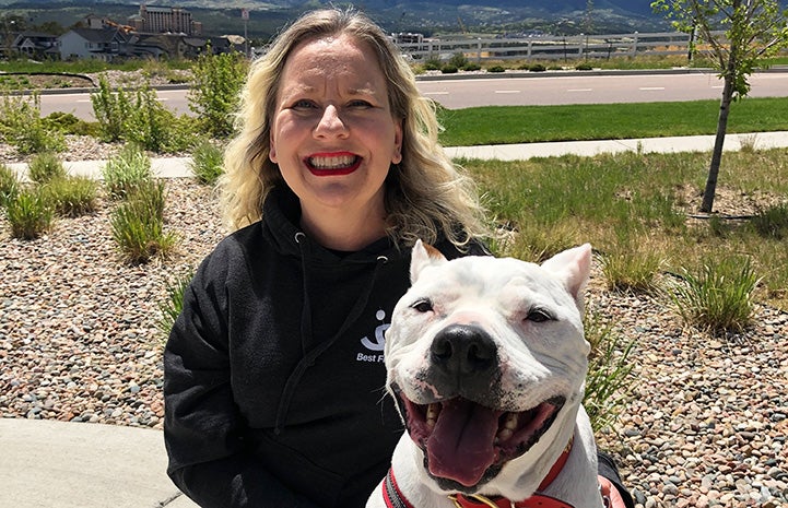 Woman posing with Ralph, the white pit bull terrier with cropped ears