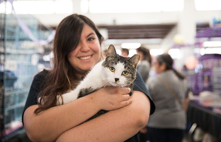 Smiling woman holding Cutie Pie the white with brown tabby cat, who has a black nose at the May the 4th NKUT Super Adoption
