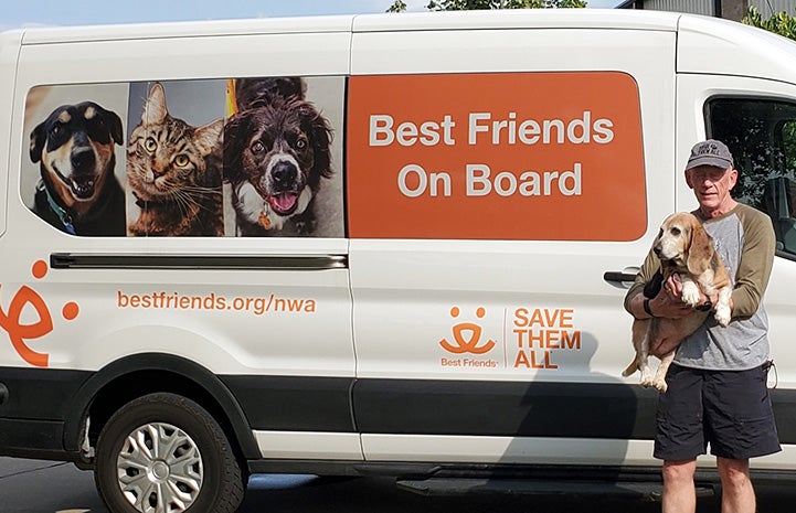 NWA volunteer Roy Horan holding a dog in front of a Best Friends transport van