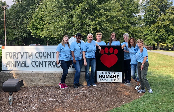 People standing in front of the Forsyth Humane Society sign