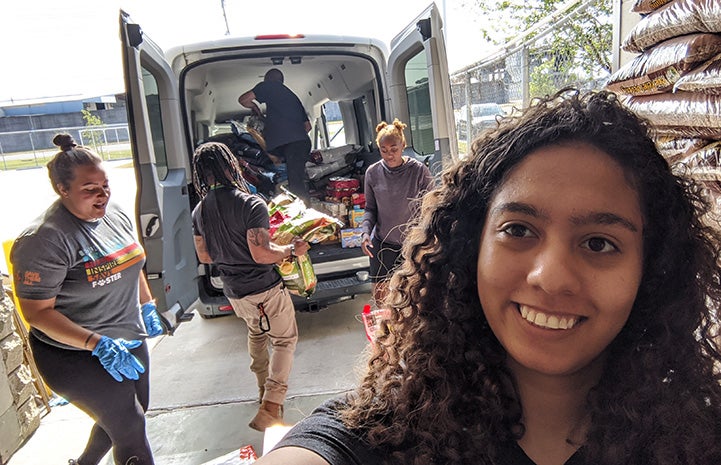 People loading a van with donated pet food to distribute