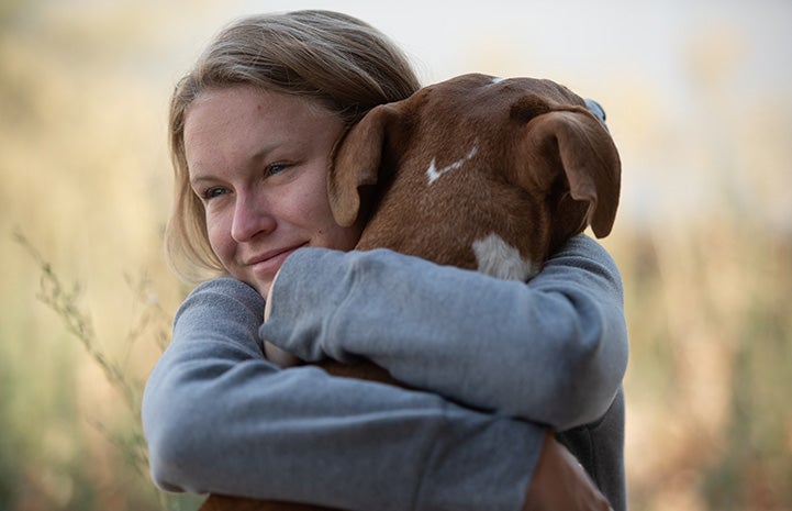 Woman hugging a brown dog