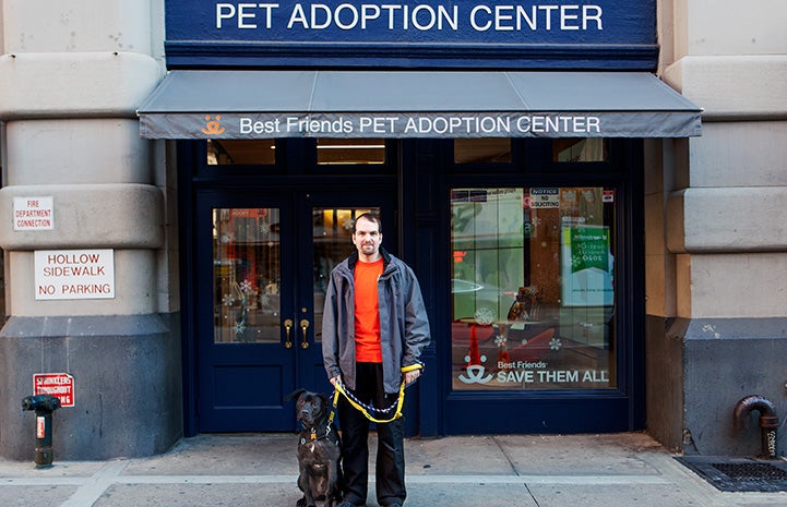 Volunteer Fabio Vitolla standing with a dog in front of the Best Friends Lifesaving Center in New York City