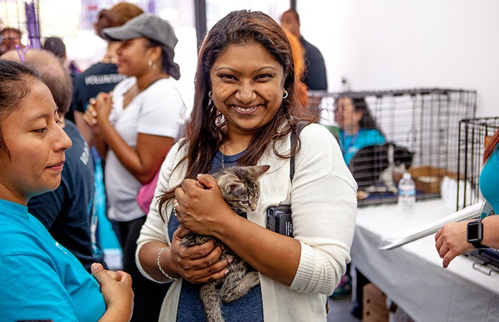 Smiling woman holding a brown tabby kitten at the New York cat adoption event