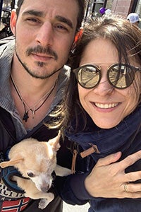 A couple holding Lara, a small brown, one-eyed foster dog