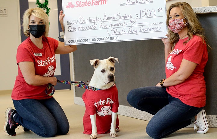 Jake from State Farm the dog with two people and an oversized check for $1,500 to the shelter from State Farm