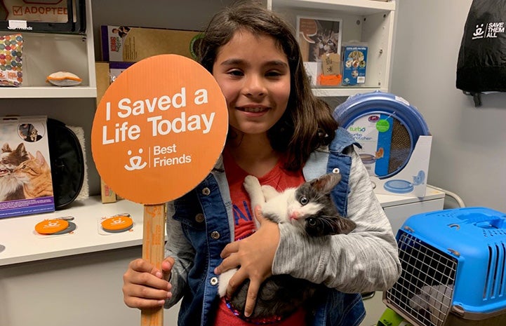 Young girl with a kitten she adopted, holding a sign that says, "I saved a life today"