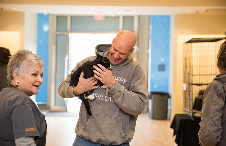 Man smiling and holding a black and white cat at the Save Them All Saturday in Salt Lake City