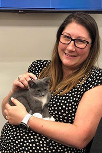 Smiling woman holding a small gray and white kitten