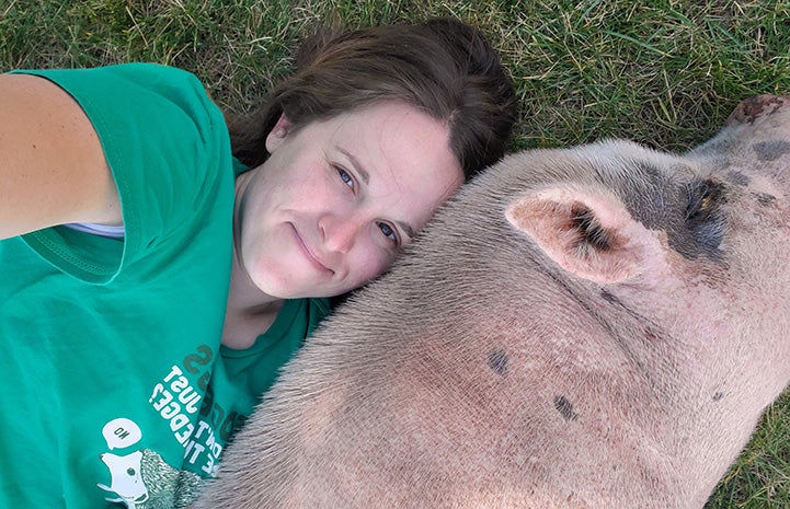 Jennifer and Diesel the pig lying with their heads next to each other on the grass